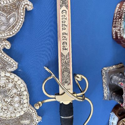 Sale Photo Thumbnail #20: Vintage Toledo Spain miniature replica sword of "Colada del Cid" featuring an ornate brass hilt and engraved blade detailing.