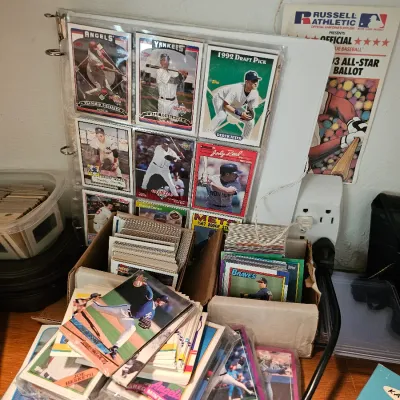 Collection of vintage baseball cards, featuring a binder page with a 1992 Topps Derek Jeter draft pick card, alongside loose stacks and...
