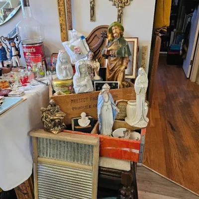 Assortment of vintage religious figurines, including several depictions of the Virgin Mary, displayed alongside a wooden washboard and...