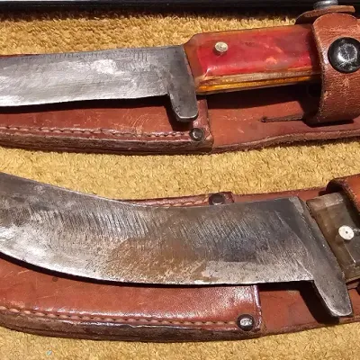 Two vintage fixed-blade hunting knives with translucent handles, shown with their corresponding brown leather sheaths.