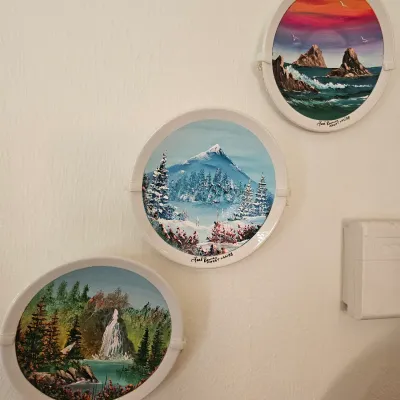 Set of three hand-painted decorative plates by Joel Romero, Mazatlan, dated 1988, featuring scenic landscapes of a sunset seascape, a...