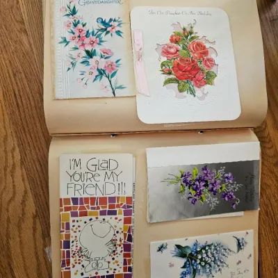 Vintage scrapbook pages displaying mid-century greeting cards, featuring floral illustrations, birthday wishes, and friendship themes.