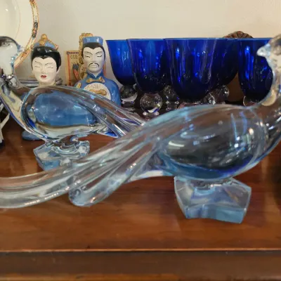 Pair of vintage light blue art glass pheasant figurines, displayed alongside cobalt blue glassware and Asian-style ceramic busts.