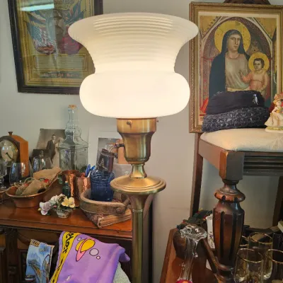 Vintage brass floor lamp featuring a ribbed white milk glass shade, surrounded by various collectibles including framed art, glassware,...