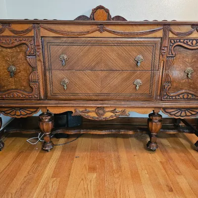 Antique Jacobean Revival style oak sideboard featuring ornate wood carvings, burl wood veneers, two central drawers, and flanking...