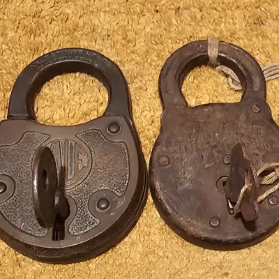 Two antique cast iron padlocks with keys, including a Yale & Towne lock, showing a weathered patina.