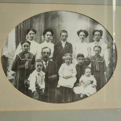 Antique black and white family portrait from the early 1900s, presented in an oval mat and framed under glass.
