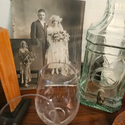Vintage black and white wedding photographs from the 1920s displayed alongside a green glass beverage dispenser and stemless wine glasses.