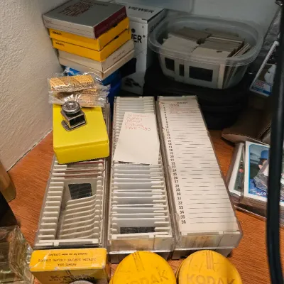 Vintage photography collection featuring Kodak slide trays, film canisters, and boxes of Kodachrome color slides.
