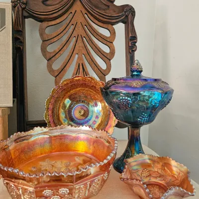 Collection of vintage carnival glass, including three marigold-colored bowls with embossed floral patterns and one blue-purple iridescent...