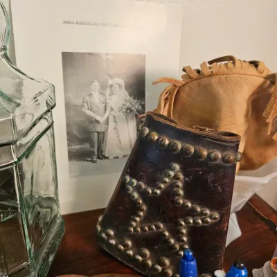 Vintage studded leather cuff with a star pattern, shown alongside a fringed suede pouch and a black-and-white wedding photograph.