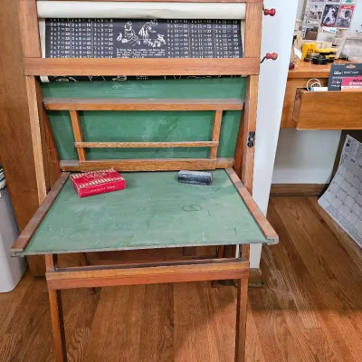 Vintage wooden children's educational desk featuring a fold-down green chalkboard surface, built-in scroll with multiplication...