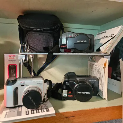 Collection of vintage Olympus cameras, including a Camedia C-700 Ultra Zoom and an Infinity SuperZoom 330, complete with manuals and a...