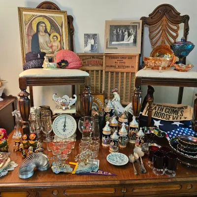Eclectic collection of vintage collectibles, including carnival glass, beer steins, nesting dolls, framed religious art, and historical...