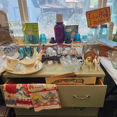 Assortment of vintage collectibles, including blue glass insulators, a 1957 Colorado license plate, patterned kitchen linens, and various...
