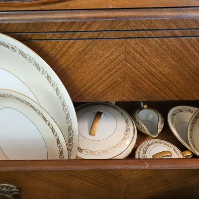 Vintage porcelain dinnerware set with gold filigree borders and accents, including platters, a covered casserole dish, and a gravy boat,...