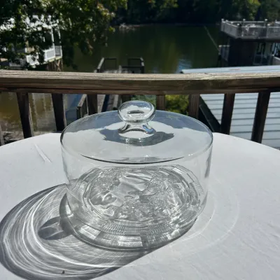 Sale Photo Thumbnail #151: Vintage clear glass cake stand with a matching dome lid, featuring an embossed floral pattern on the base.