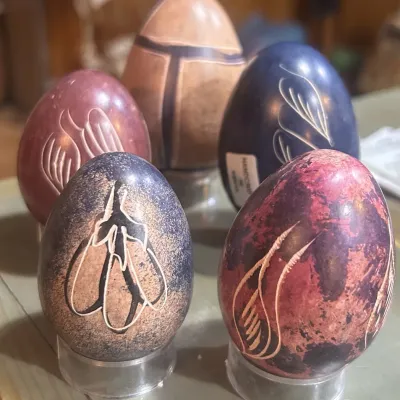 Sale Photo Thumbnail #138: Collection of five hand-carved soapstone eggs featuring various colors, textures, and etched floral and abstract designs, displayed on clear plastic stands.