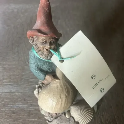 Sale Photo Thumbnail #57: Vintage Tom Clark gnome figurine named 'Johann', numbered 1075 and dated 1984, featuring a gnome with a seashell and the original paper tag.