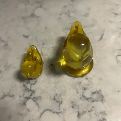Sale Photo Thumbnail #53: Pair of vintage amber art glass bird figurines, featuring a larger and smaller stylized bird in a warm yellow-gold hue.