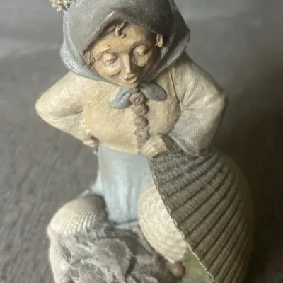 Sale Photo Thumbnail #58: Vintage resin figurine depicting a woman in a bonnet gathering seashells, featuring a textured design with muted earth tones.