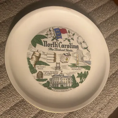 Sale Photo Thumbnail #48: Vintage North Carolina souvenir plate featuring illustrations of state landmarks including Chimney Rock, the Wright Brothers Memorial, and the State Capitol.