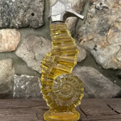 Sale Photo Thumbnail #69: Vintage Avon seahorse-shaped glass perfume bottle with a silver-tone metal cap, containing yellow liquid.