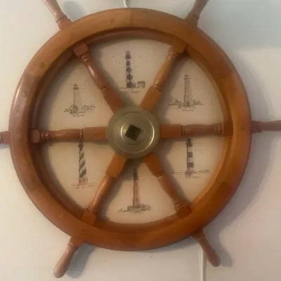 Sale Photo Thumbnail #60: Vintage wooden ship's wheel wall decor featuring a central fabric insert illustrated with various lighthouses.