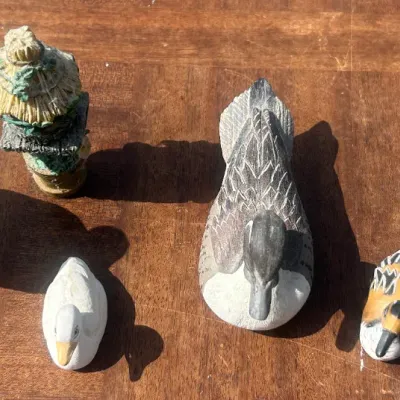 Sale Photo Thumbnail #49: Collection of six miniature duck figurines, including carved wood and ceramic styles, displayed on a wooden surface.