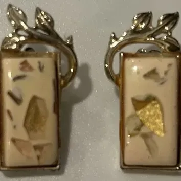 Sale Photo Thumbnail #131: Pair of mid-century modern clip-on earrings featuring rectangular cream-colored resin inserts with gold-tone leaf and branch accents.