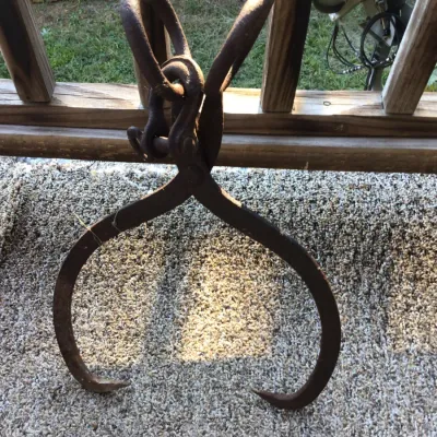 Sale Photo Thumbnail #165: Vintage cast iron logging or ice tongs with a heavy-duty hanging ring, showing a weathered, rusted patina.