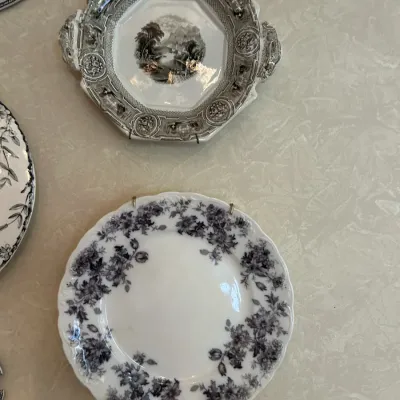 Two vintage transferware plates, including a black and white floral patterned plate with a scalloped edge and an octagonal handled plate...