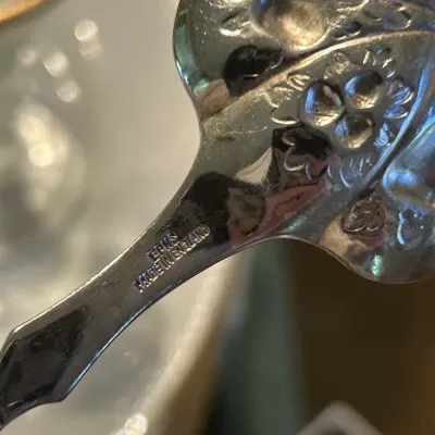 Close-up of an EPNS silver-plated spoon back, showing the "EPNS MADE IN ENGLAND" hallmark and an embossed floral pattern.
