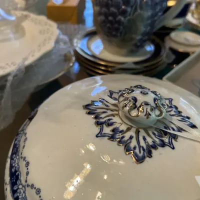 Vintage porcelain lidded serving dish featuring a blue and white floral pattern with gold accents, shown alongside other collectible...