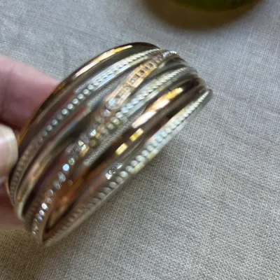 Vintage multi-strand Lucite bangle bracelet featuring alternating bands of clear, metallic gold, and silver-tone glitter details.