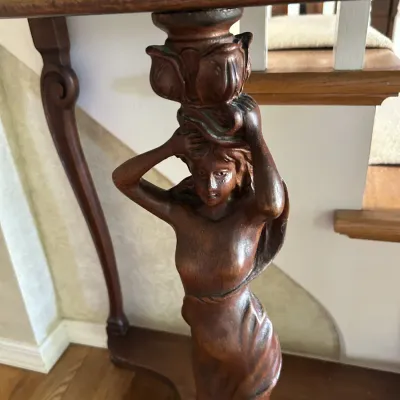 Sale Photo Thumbnail #117: Art Nouveau style wooden console table featuring a carved female caryatid support column and a glass-topped surface.