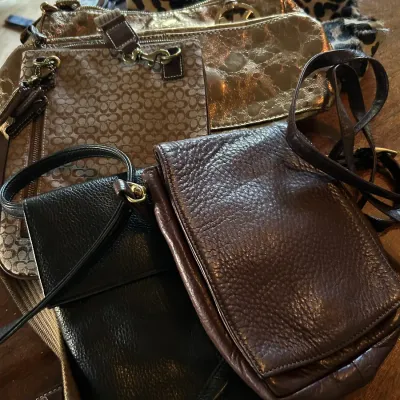 Sale Photo Thumbnail #104: Collection of designer and leather handbags, including a Coach signature canvas crossbody, a metallic gold Michael Kors shoulder bag, a leopard print purse, and textured leather crossbody bags.