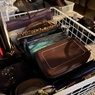 Assorted vintage and modern clutches, wallets, and small handbags organized in a white wire basket.