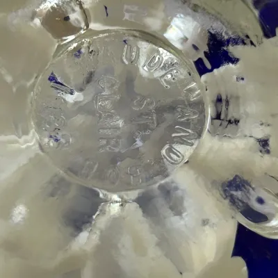 Close-up of the maker's mark on the base of a Joe St. Clair art glass paperweight, dated 1983.