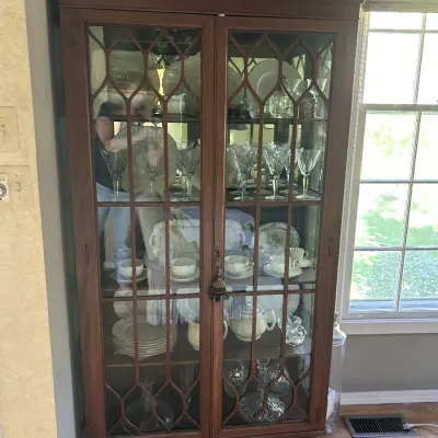 Sale Photo Thumbnail #122: Chippendale-style mahogany china cabinet featuring a broken pediment top with a central finial, glass doors with decorative mullions, and ball-and-claw feet.