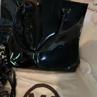 Michael Kors black patent leather tote bag, shown with its original white dust bag.