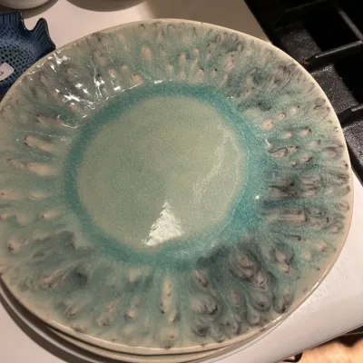 Stack of ceramic plates featuring a crackle glaze in shades of turquoise, seafoam green, and white.