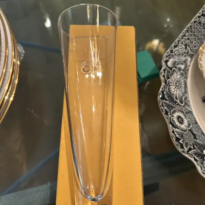 Sugahara clear glass bud vase with a heavy, solid base, shown resting on its original cardboard box.