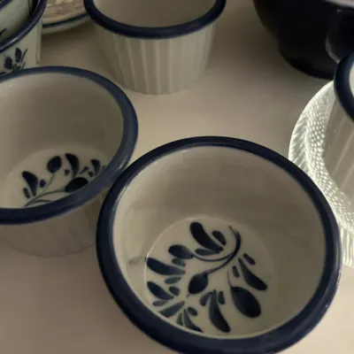 Set of white ceramic ramekins featuring a blue rim and a hand-painted blue leaf motif on the inside bottom.