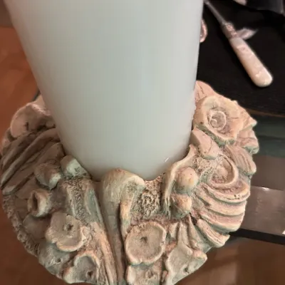 Decorative resin or plaster candle ring featuring sculpted seashells and coral motifs, holding a thick white pillar candle.