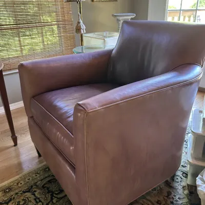 Sale Photo Thumbnail #121: Contemporary leather armchair in a dusty rose or mauve hue, featuring a deep seat cushion and tapered dark wood legs.