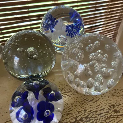 Collection of four vintage glass paperweights, including two with controlled bubble designs and two with blue floral inclusions.
