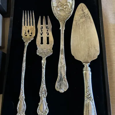 Four-piece vintage silver-plated serving set, including a meat fork, pickle fork, berry spoon, and cake server, featuring ornate floral...