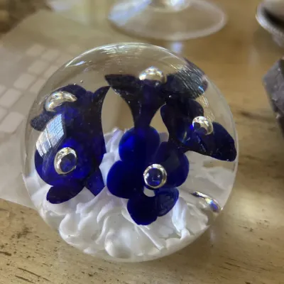 Vintage art glass paperweight featuring cobalt blue flowers with controlled bubbles over a white spatter base.