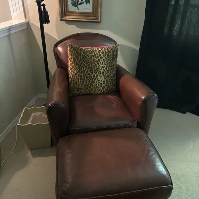 Sale Photo Thumbnail #110: Classic brown leather armchair and matching ottoman, paired with a leopard print accent pillow.